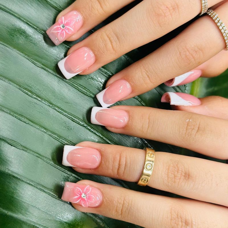 White French tips with pink 3D flower accents by Nini Nail Bar